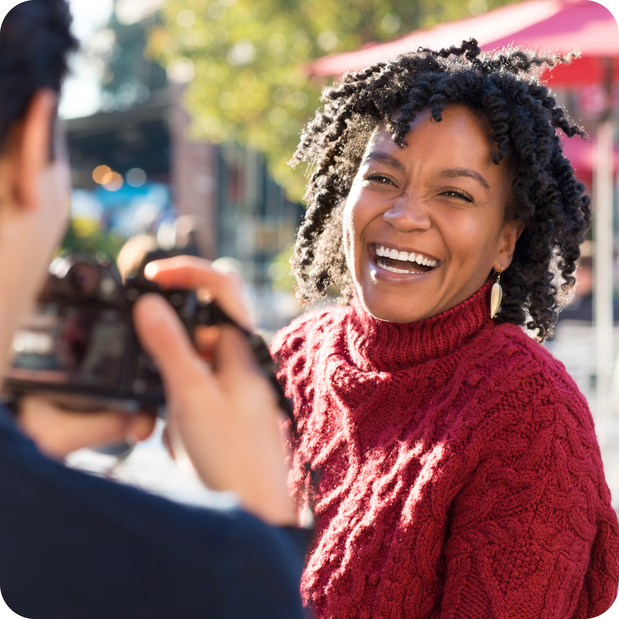 young happy black woman smiling wearing a red sweater getting her online dating photo taken by her photographer